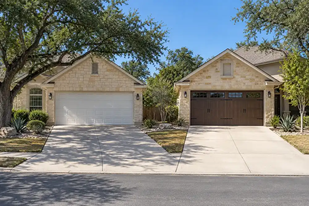 Two limestone homes with a white raised-panel garage door and a brown carriage-style door with windows