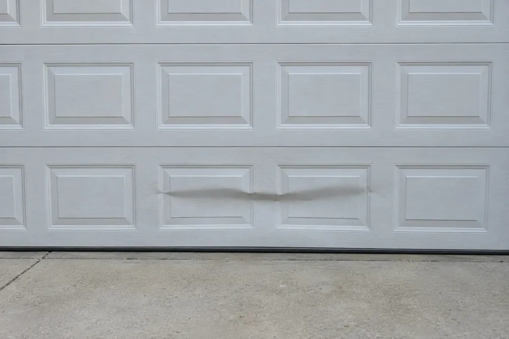 Sharp crease across the bottom section of a white steel garage door