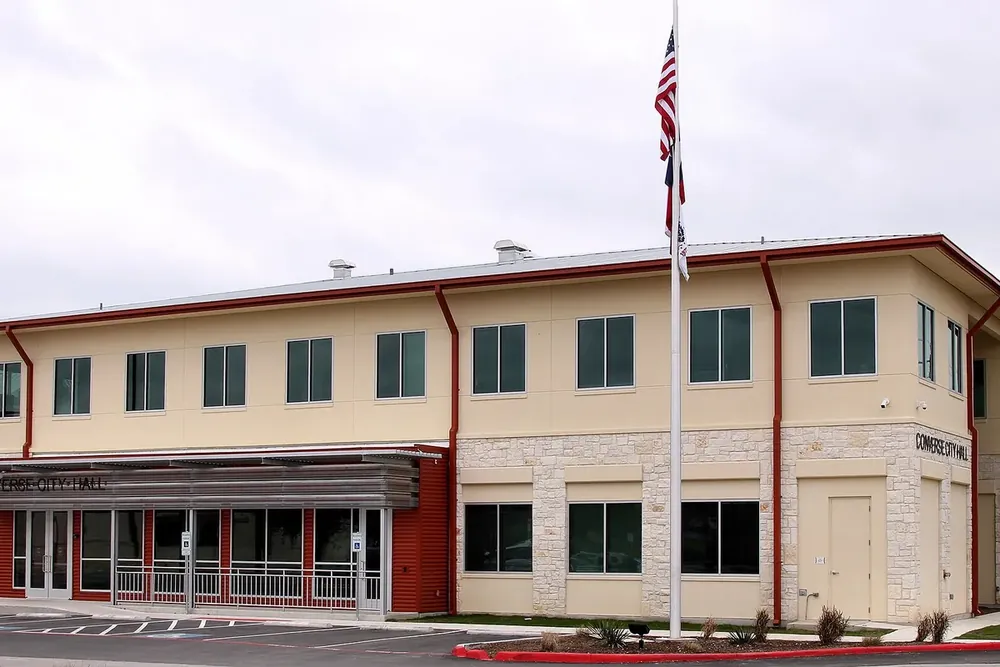 The two-story Converse City Hall with stone trim and a flagpole in Converse, Texas