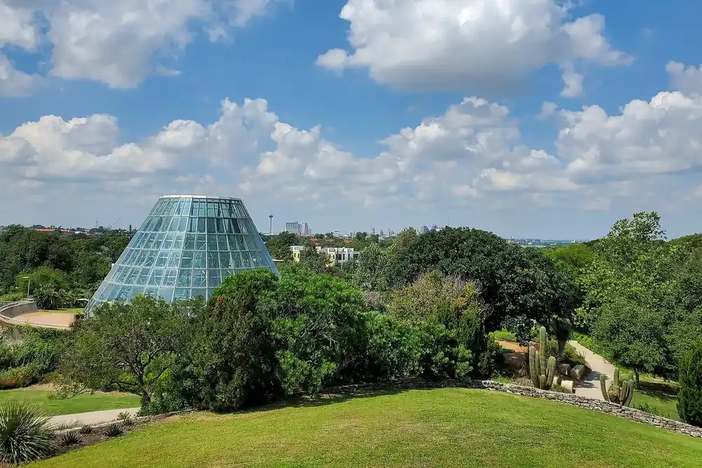 The glass conservatory of the San Antonio Botanical Garden with the downtown skyline beyond, San Antonio, Texas